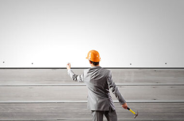 Rear view of businessman fixing white blank banner with hammer