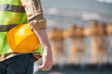 Arm holding yellow hard hat against hip
