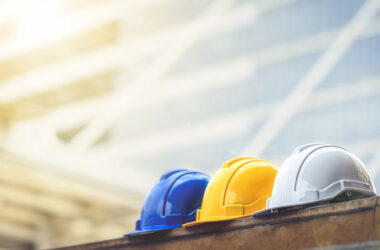 white, yellow and blue hard safety helmet hat for safety project of workman as engineer or worker, on concrete floor on city.