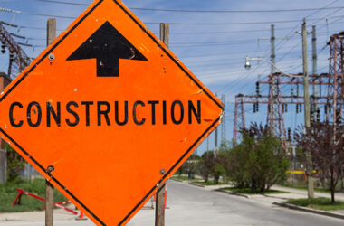 Bright Orange Construction sign by the of a road
