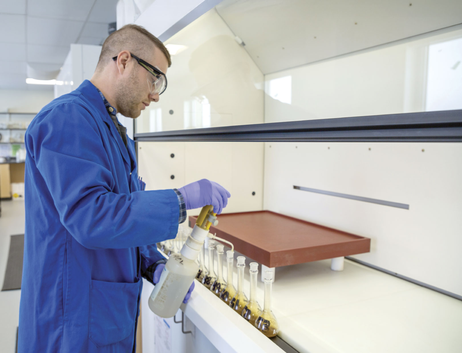 Man in lab wearing lab coat and safety goggles and gloves