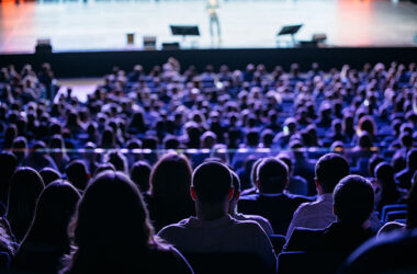 People listen to the speaker on the forum in the conference room. Blue lighting