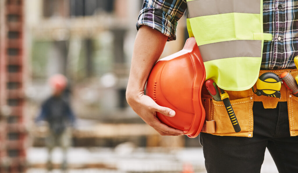 Construction worker holding a safety red helmet while standing outdoors