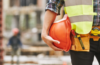 Construction worker holding a safety red helmet while standing outdoors