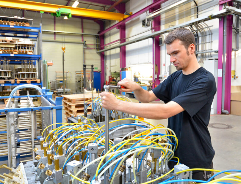 Operator repairs a machine in an industrial plant with tools - pneumatics and hydraulics