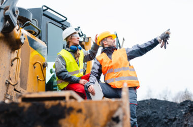 Man and woman as workers on excavator in quarry pointing at things