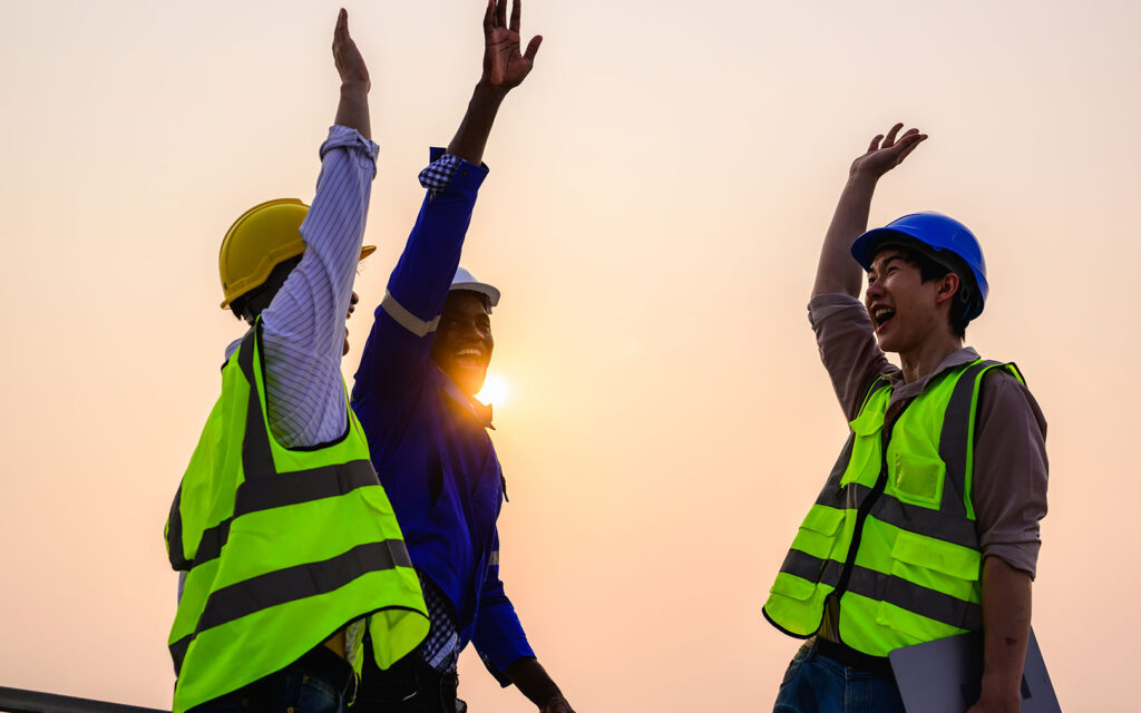 Smiling workers in PPE equipment gathering for a high five