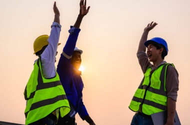 Smiling workers in PPE equipment gathering for a high five