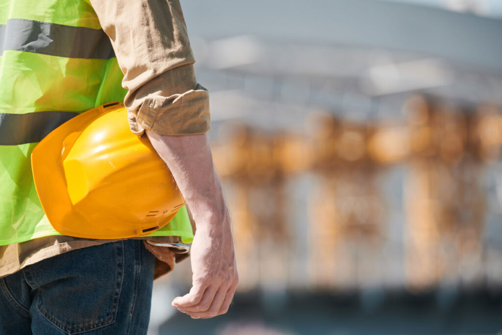 Arm holding yellow hard hat against hip
