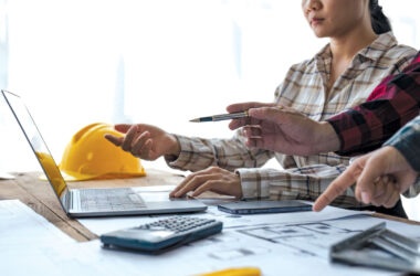 A team of architects collaborates on a building project with construction tools nearby hinting at the work ahead