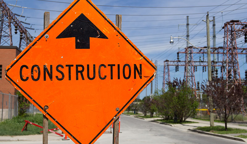 Bright Orange Construction sign by the of a road