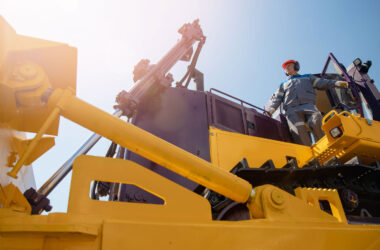 Equipment operator standing on vehicle with bright sun in background