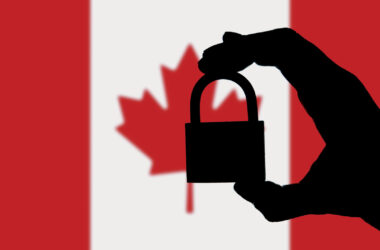 Silhouette of hand holding a padlock with Canadian flag in background