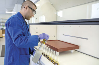 Man in lab wearing lab coat and safety goggles and gloves
