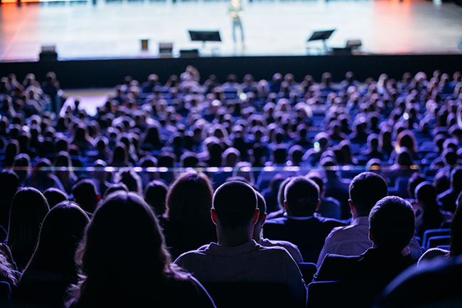 People listen to the speaker on the forum in the conference room. Blue lighting