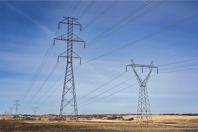 Power industry transmission towers and communication lines standing tall on the Canadian prairies in Rocky View County Alberta Canada.