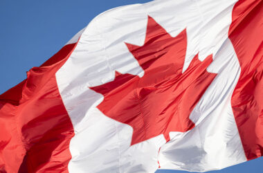 Red and white Canadian flag with a maple leaf waving in the air.