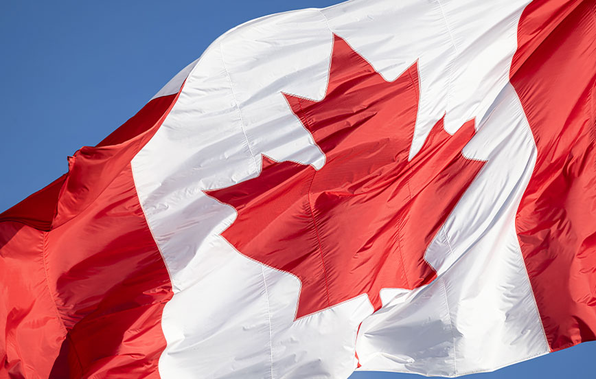 Red and white Canadian flag with a maple leaf waving in the air.