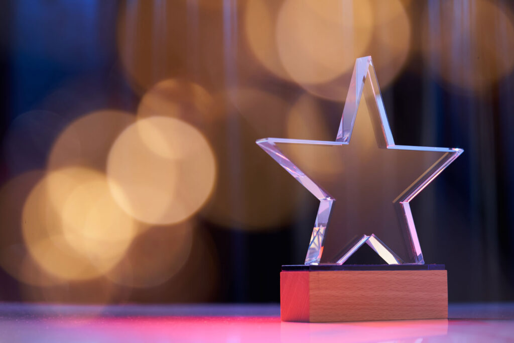 Star shape trophy with color light against stage curtain as background