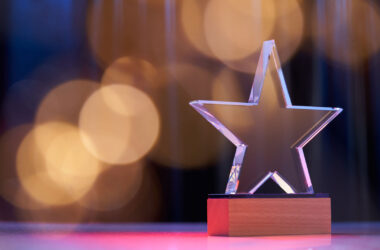Star shape trophy with color light against stage curtain as background