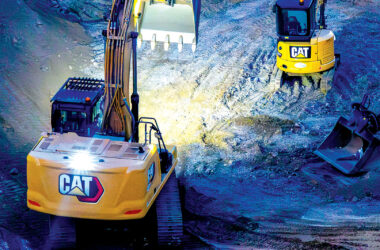 Two excavators working on a construction site at night.