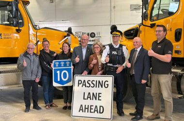 Shantell Lipp and other people posing for a picture with 2 big yellow trucks in the background.