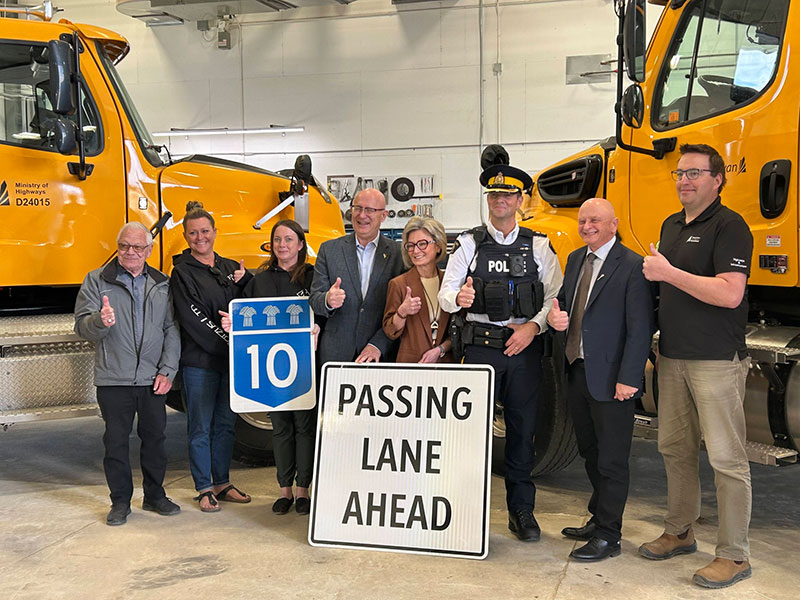 Shantell Lipp and other people posing for a picture with 2 big yellow trucks in the background.