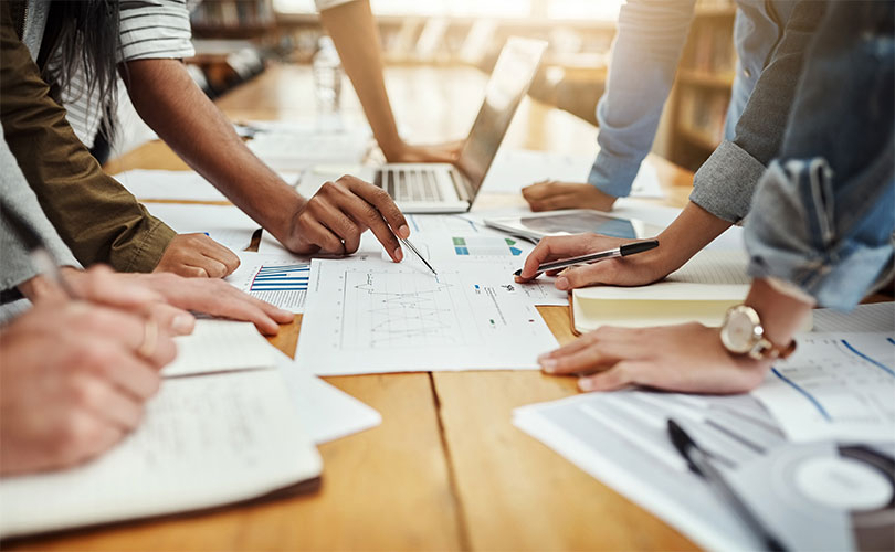 Office workers hands on table along with various paper and pens