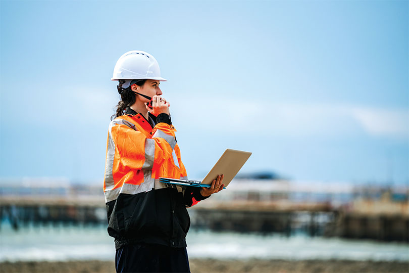 Worker holding laptop and radio in industrial area