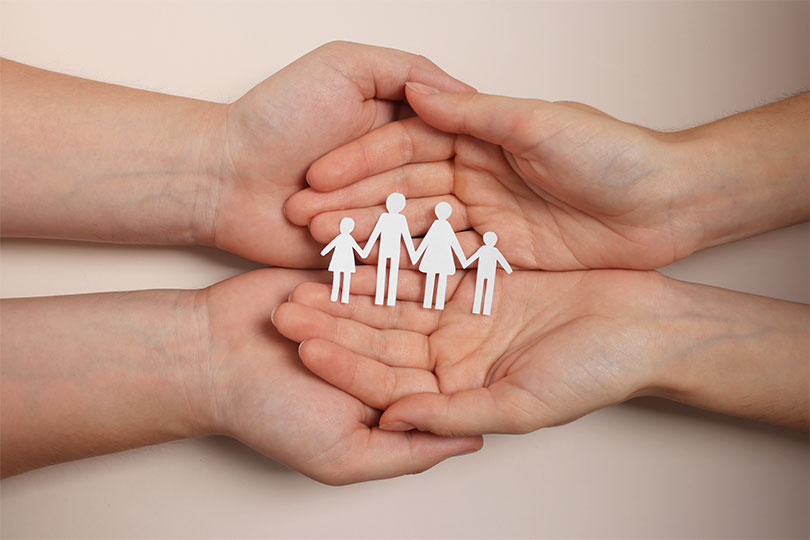 Couple holding paper family figures on beige background