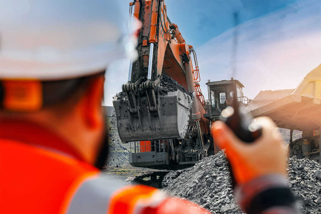 Open pit with heavy machinery and worker observing operations
