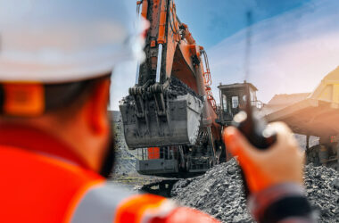 Open pit with heavy machinery and worker observing operations