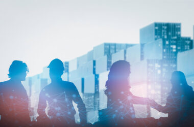 Silhouette of people with shipping containers in background