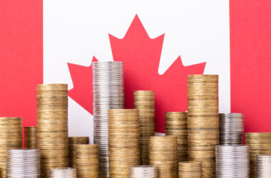 Golden and silver money stacks in front of flag of Canada